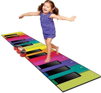 A young girl is happily dancing on a large, colorful floor piano mat.