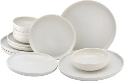 A collection of off-white ceramic plates and bowls are arranged on a white background.