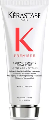 A product shot of a white tube of Kerastase Premiere Repairing Conditioner with red and black text and branding.