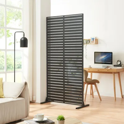 A modern living room or office space with a sofa, a desk with a computer, and a room divider.