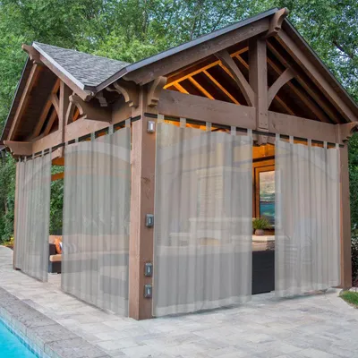 A gazebo with curtains next to a pool.