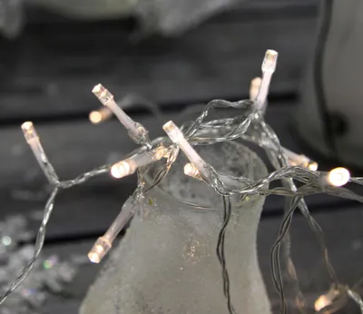 A close-up of a string of LED lights wrapped around a frosted glass vase.
