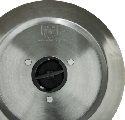 Close-up view of the bottom of a metal appliance, showing a central black component with blades and surrounding metal.