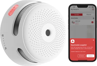 A white smoke detector is shown next to a smartphone displaying an alert from a smart home app.