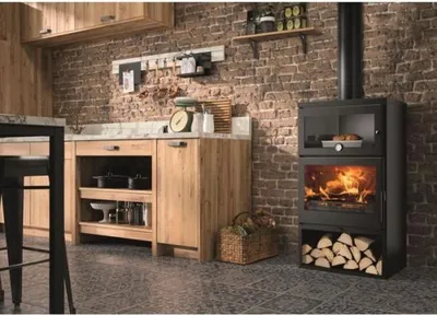 A kitchen with a wood-burning stove, wooden cabinets, and brick walls.