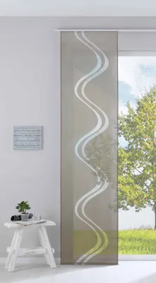 A panel curtain with a wavy pattern hangs in front of a window with a view of trees and grass.