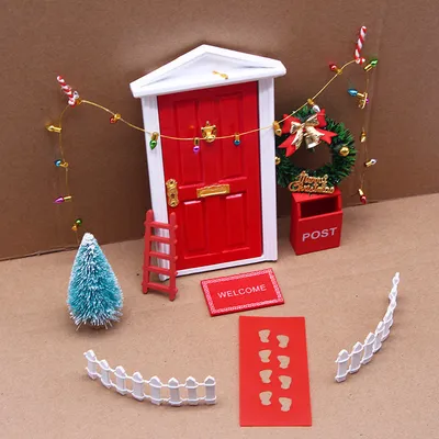 A miniature Christmas-themed fairy door set arranged on a brown surface.
