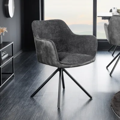 A dark gray velvet armchair with black metal legs is shown in a modern living room setting, with a large window in the background.