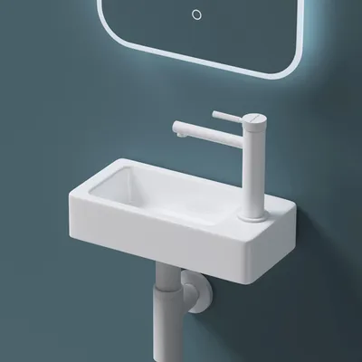 A close-up shot of a white ceramic sink with a white faucet mounted on a teal wall.