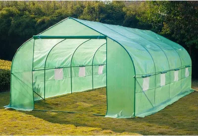 A green tunnel greenhouse set up on a grassy lawn with trees in the background.