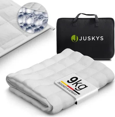 A folded white weighted blanket is shown with a close-up inset of its filling and a black carrying bag with the brand logo.