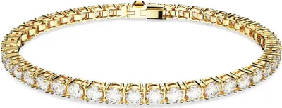 A close-up studio shot of a gold tennis bracelet with clear stones.