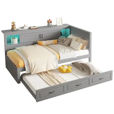 A gray daybed with a pull-out trundle bed, styled with bedding and decorative items.