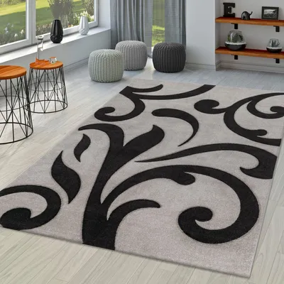 A modern living room with a rug, side tables, and poufs.