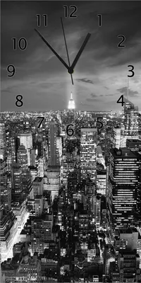 Produktbild von Wallario Design Wanduhr bedruckt, Größe 30 x 60 cm, Motiv: New York bei Nacht - Panoramablick über die Stadt - schwarzweiß