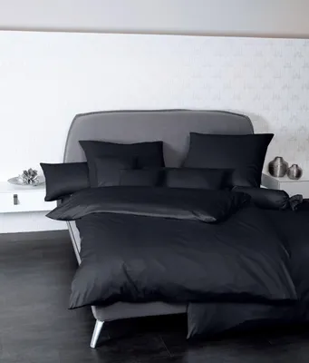 A neatly made bed with black bedding and pillows in a bedroom setting.