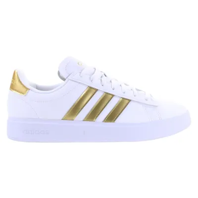A white Adidas sneaker with gold stripes and accents, shown from the side against a white background.