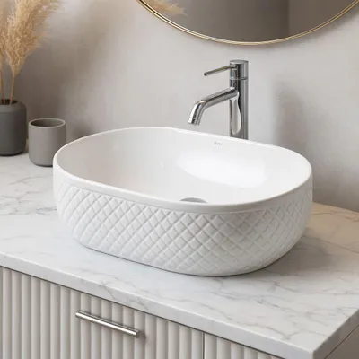 A white ceramic vessel sink with a textured pattern sits on a marble countertop.
