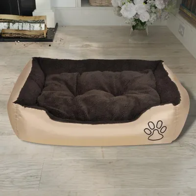 A dog bed placed on a wooden floor in a room with a fireplace and flowers.