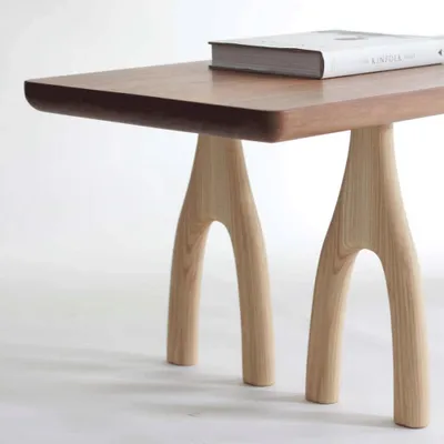 A close-up shot of a modern wooden table with a book on top.