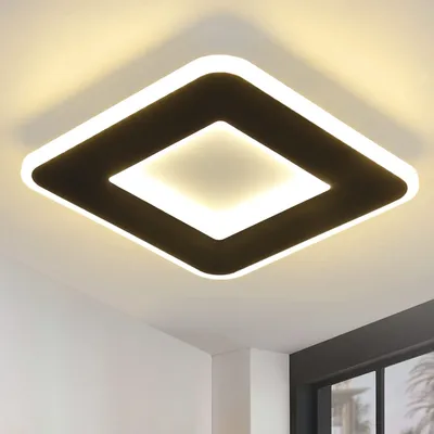 A modern square ceiling light with a black frame and a white illuminated center, mounted on a white ceiling.