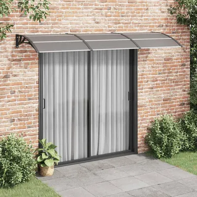 A door awning installed above a sliding glass door on a brick wall.