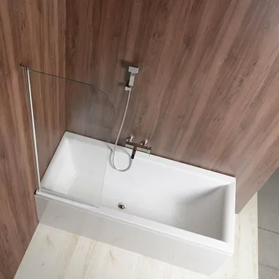 A bathtub with a glass shower screen and a shower head attached to a wooden wall.