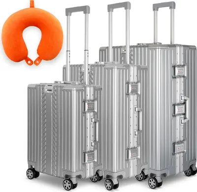A set of three silver suitcases of varying sizes and an orange neck pillow are displayed against a white background.