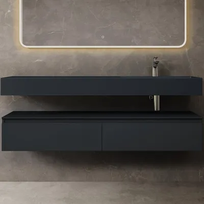 A modern bathroom vanity with a sink and drawers against a marble-tiled wall.