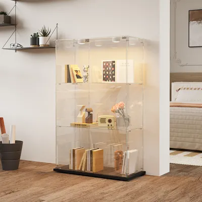 A glass display cabinet with LED lighting is shown in a room with a bed in the background.