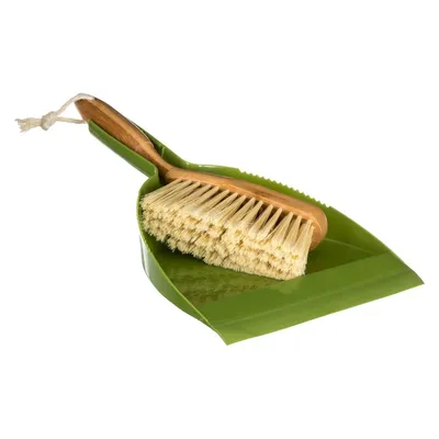 A green dustpan with a wooden-handled brush resting on it, isolated on a white background.