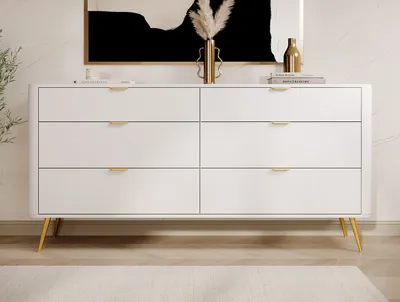 A white dresser with gold legs and handles is shown in a room with a marble wall and a rug.