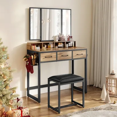 A vanity table with a tri-fold mirror, stool, and Christmas decorations.