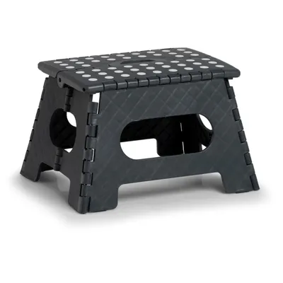 A dark gray folding step stool with white dots on the top surface, shown from a three-quarter front angle against a white background.