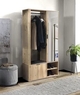 A hallway wardrobe with a mirror, coat rack, and shoe storage, next to a grey ottoman and a potted plant.