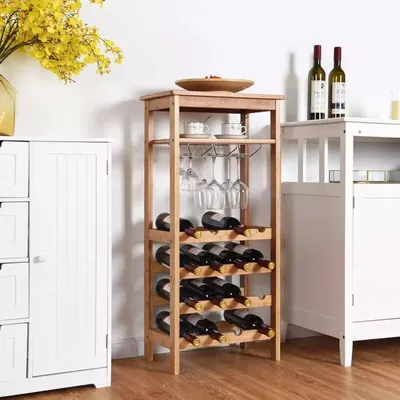 A wooden wine rack filled with wine bottles and wine glasses, placed next to a white cabinet.