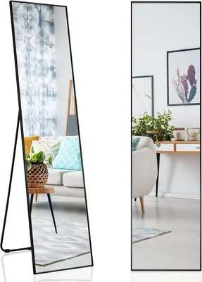 A full-length mirror with a black frame is shown in a living room setting, reflecting a sofa and curtains.