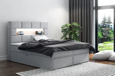 A bedroom scene with a bed, plant, and large window overlooking a garden.