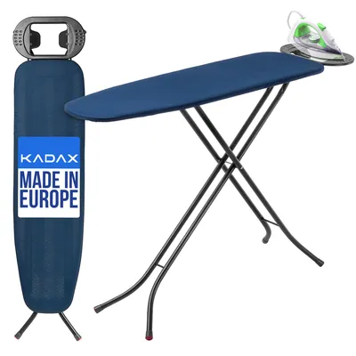 A dark blue ironing board with a built-in iron rest is shown, with a green and white iron on the rest. The ironing board is folded and standing upright on the left, and open and set up on the right. A label on the upright ironing board reads 'KADAX MADE IN