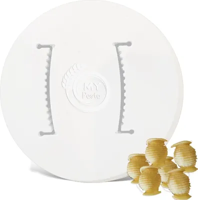A white pasta maker attachment with several small pasta shapes in the foreground.