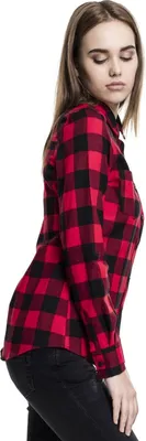 A woman wearing a red and black checkered flannel shirt and black jeans, shown from the side against a white background.