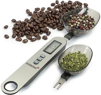 A digital spoon scale with coffee beans, peppercorns, and dried herbs.