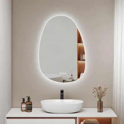 A modern bathroom vanity with a sink and a large, illuminated, irregularly shaped mirror above it.