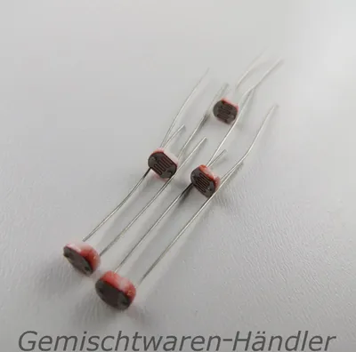 Several electronic components, likely photoresistors, are arranged on a light-colored surface.
