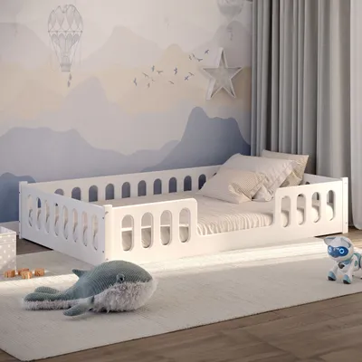 A child's bed with protective rails in a room with a mountain-themed mural and curtains.