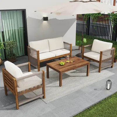 An outdoor patio set with a sofa, armchair, and coffee table, set up on a tiled patio with grass and a fence in the background.