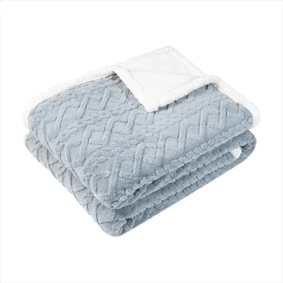 A folded blue blanket with a white sherpa lining is shown against a white background.
