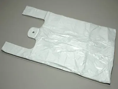 A single white plastic shopping bag is laid out on a gray surface.
