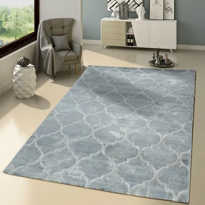 A modern living room with a gray rug, armchair, and a white cabinet.