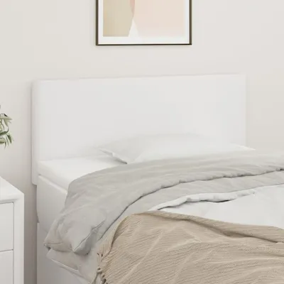 A white headboard is shown on a bed with bedding.
